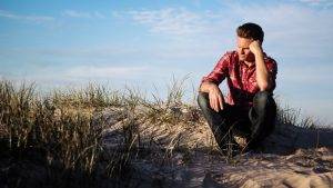 man thinking sitting on rock